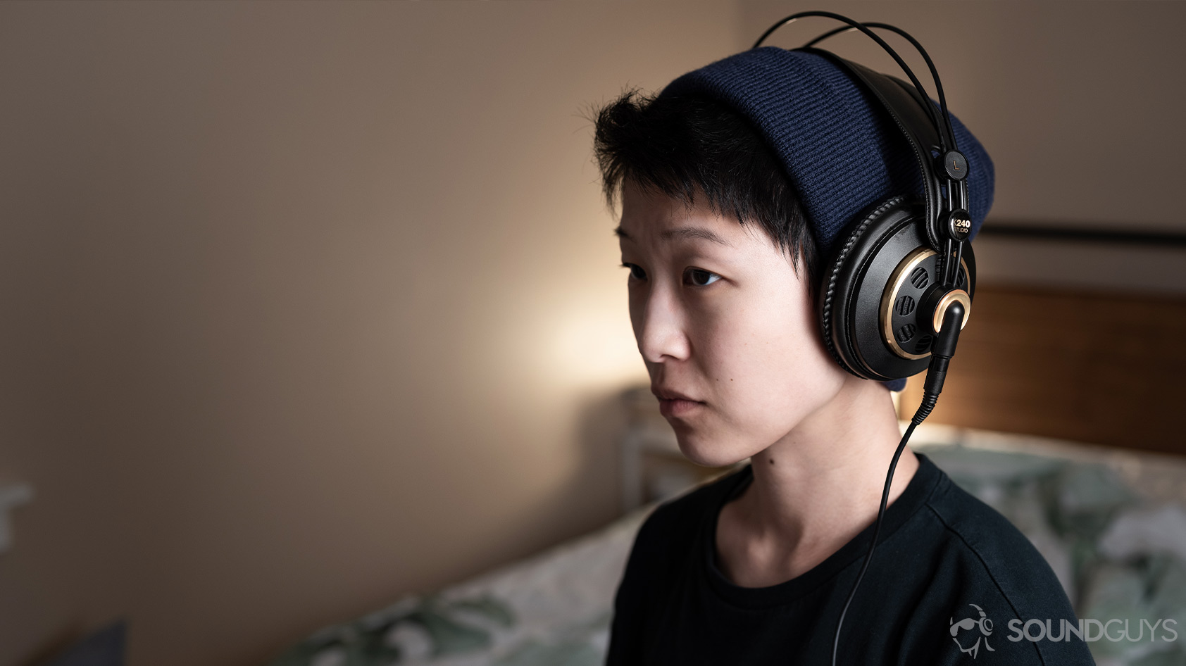 A photo of the AKG K240 Studio semi-open headphones being worn by a woman angled slightly away from the camera.