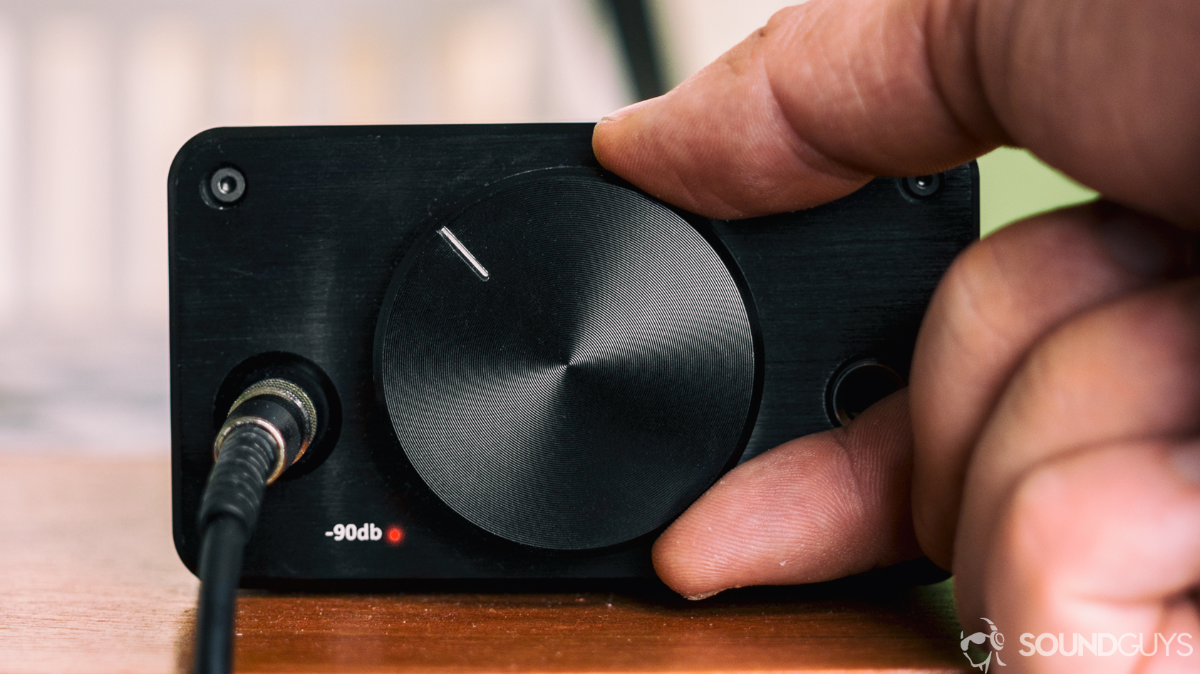 best computer speakers: A photo of a hand turning up the knob of a headphone amplifier