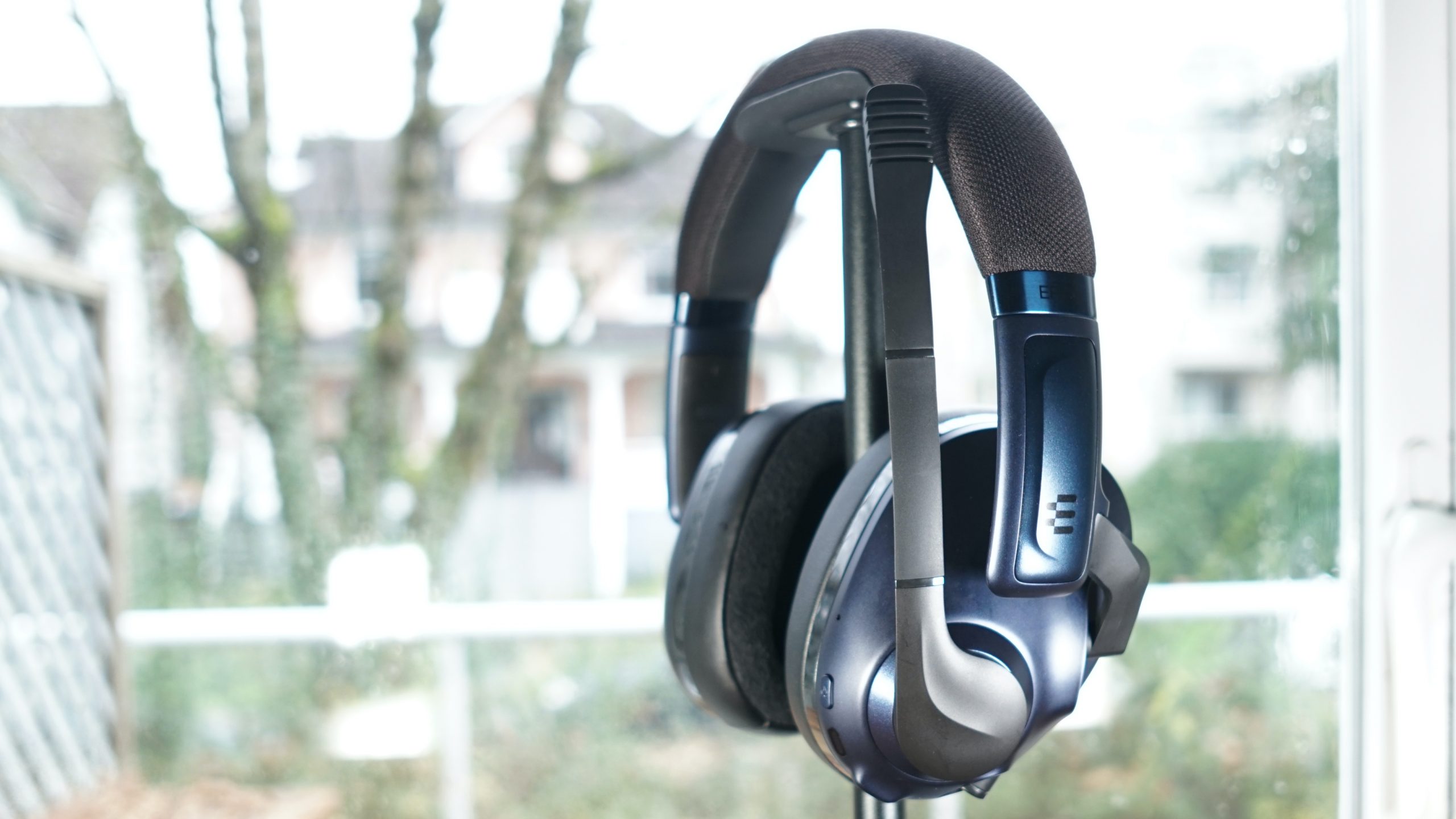 The EPOS H3PRO Hybrid gaming headset sits on a headphone stand