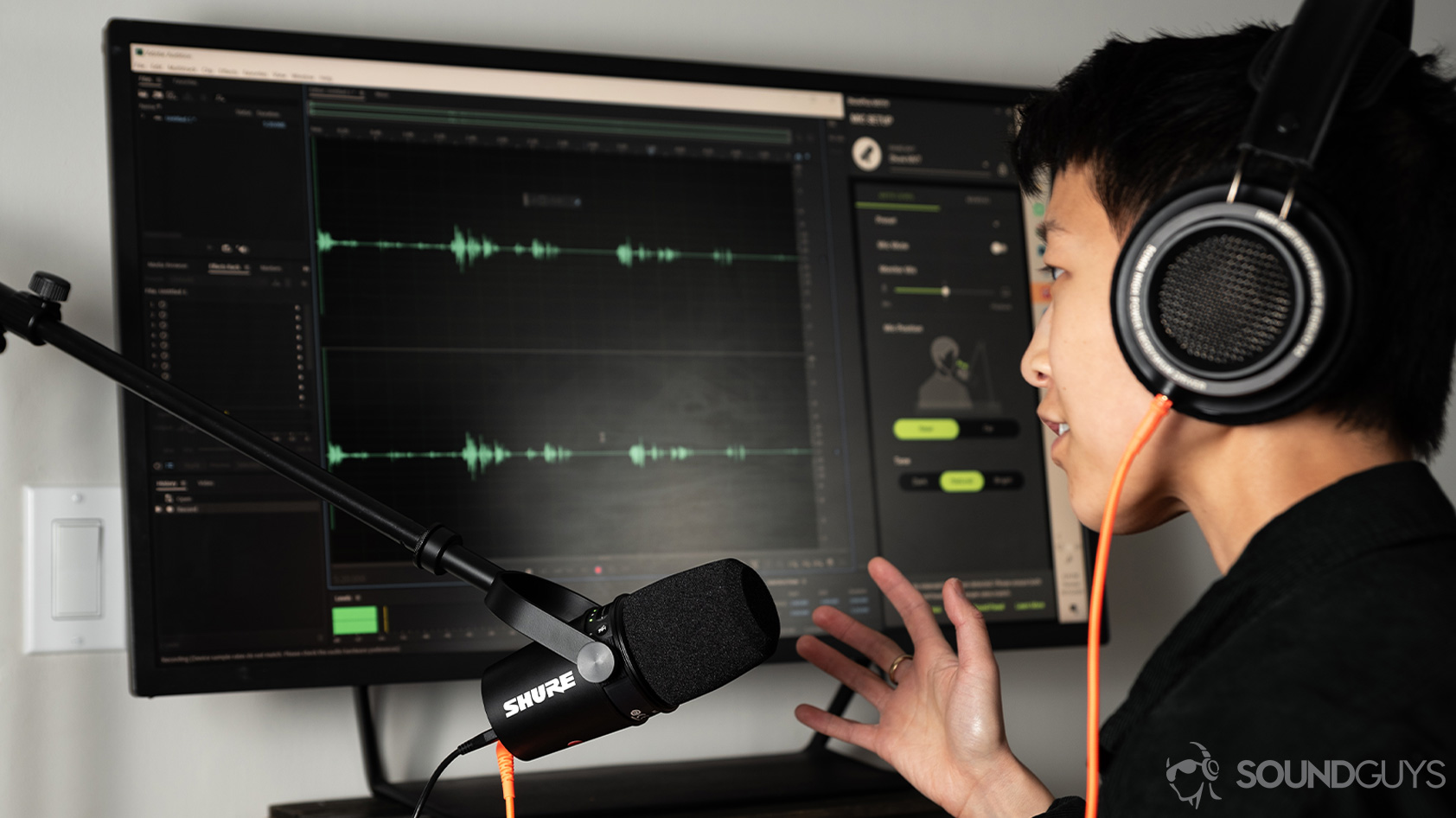 A person speaks into the Shure MV7 USB microphone as it records into Adobe Audition.